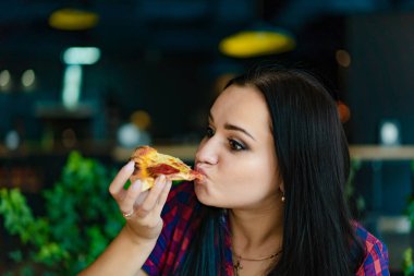güzel kız kafede lezzetli bir dilim peynir ve sos ile pizza yiyor. Esmer sulu pizza pizza iç arka plan üzerinde sahiptir