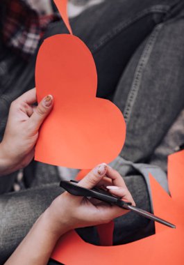 Kadınların elleri tutun makas ve hazır el yapımı kağıt Kalp Sevgililer günü vardır. Yakın çekim