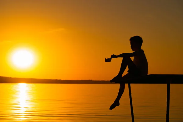 Ein Kleiner Junge Sitzt Mit Einem Papierboot Der Hand Bei — Stockfoto
