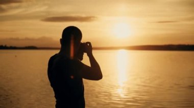 Fotoğrafçı çekim nehre günbatımı zamanında silüeti.