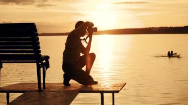 Fotoğrafçı çekimi sırasında günbatımı manzara resmini. Günbatımında nehirde yüzme insan silüeti