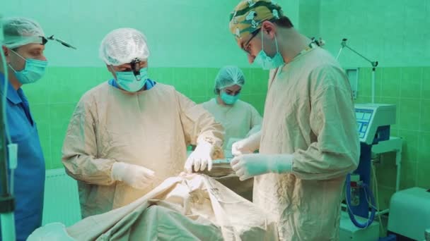 制服で外科医のチームは 外科医院で患者に対して操作を実行します — ストック動画