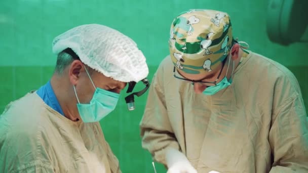 制服を着た つの外科医が外科病院で患者に対して操作を実行します — ストック動画