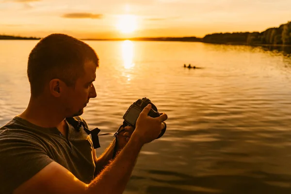 Stilig Man Tittar Professionell Foto Kameran Nära Floden Vid Solnedgången — Stockfoto