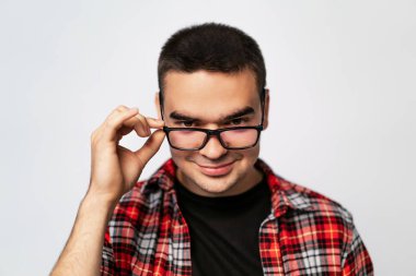 Beyaz stüdyo yakın çekim gözlük gülümseyen genç trendy biri vurdu. Yeni gözlük kameradan bakarak ve bunları test t-shirt zeki adam portresi.