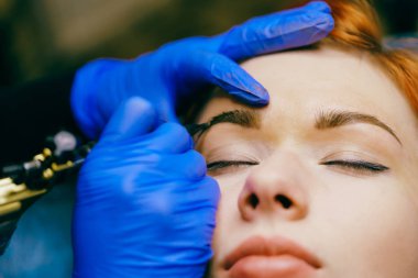 Güzellik salonunda profesyonel kaş dövmesi olan güzel bir kadın. Kalıcı makyaj kaşları ameliyat. Yakın, seçici odak.