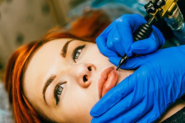 Dudaklarından sürekli makyaj uygulayarak makyajcısı. Kalıcı Dudak Makyajı dövme salonda prosedürü geçiren genç kadın.