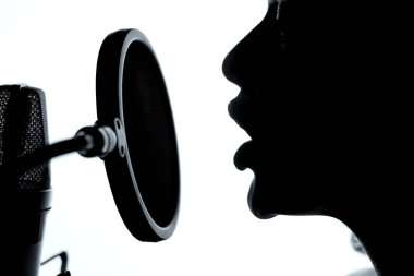Şehvetli kadın siluet stüdyo mikrofon yakınındaki güzel yüzü kasalı. Mikrofon önünde açılan ağzı bir kız. Yakın çekim
