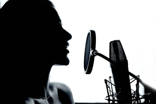 女歌手在录音室的麦克风前表演音乐 一个女人的个人资料与麦克风在工作室 黑色和白色 — 图库照片