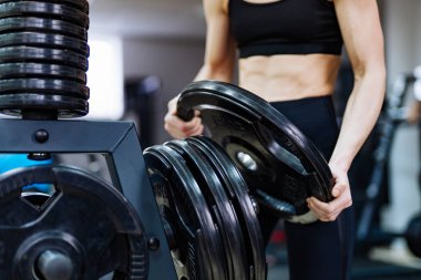 Halter diskten holding ve spor salonunda demir disklere koyarak güçlü kadının elleri. Kas Genç kadın halter demir diskini tutan.