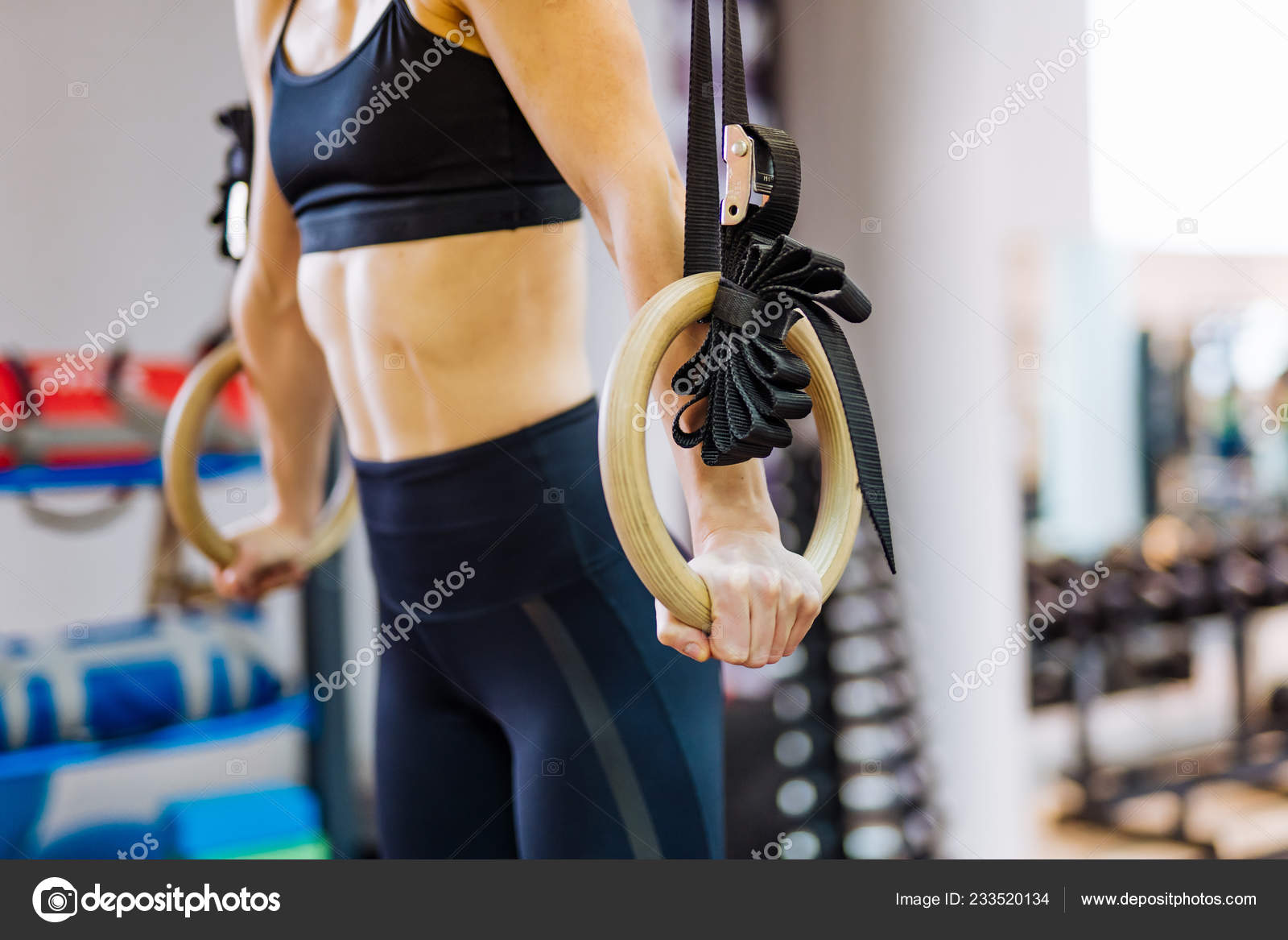 Sporty woman using gymnastic rings/ Sporty women in a gym exercising with gymnastic  rings Stock Photo