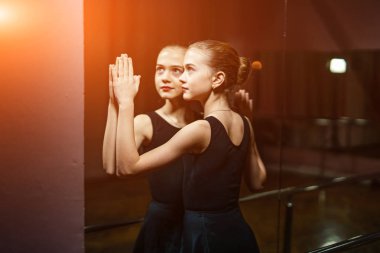 Siyah ayna dokunmadan balerin ve stüdyo arka plan üzerinde yansıması içindeki görür. Genç balet aynaya poz ve yansıtır