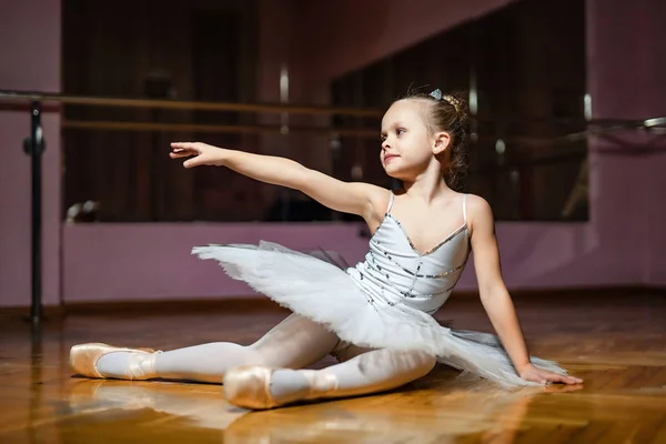 Bedårande Liten Ballerina Vitt Tutu Sitter Trägolv Och Pekar Med — Stockfoto