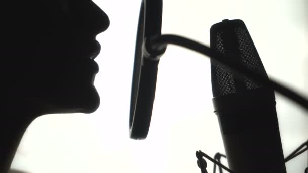 Sziluettjét egy nő énekel egy dalt a stúdióban. Fekete-fehér.