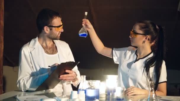 실험실에서의 화학자들은 플라스크를 액체로 검사합니다 과학에 — 비디오