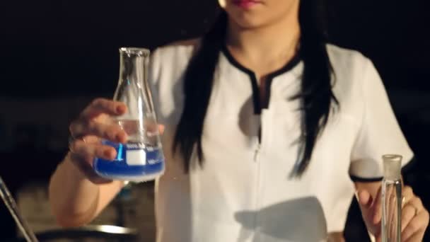 化学实验室的实验 年轻女子科学家混合试剂从玻璃烧瓶 — 图库视频影像