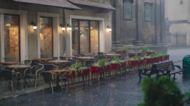 yağmur damlaları masa ve sandalyeler restoranın sokakta üzerinde düşer. Yola yakın saksı ile ıslak yaz teras mevcuttur
