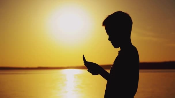 Хлопчик Робить Орігамі Вигляді Корабля Тлі Заходу Сонця Біля Річки — стокове відео