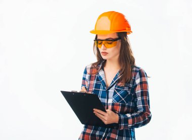 Beyazlara izole edilmiş iş planları olan güzel, ciddi bir kadın mimar. Kasklı ve gözlüklü çekici işçi siyah klasör tutuyor.