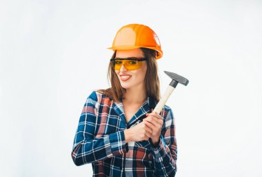 Genç ve güzel kız portakal kask ve koruyucu gözlük ayakta ve beyaz arka plan üzerinde kameraya bakarak çekiçle. Mühendislik ve endüstriyel kavramı