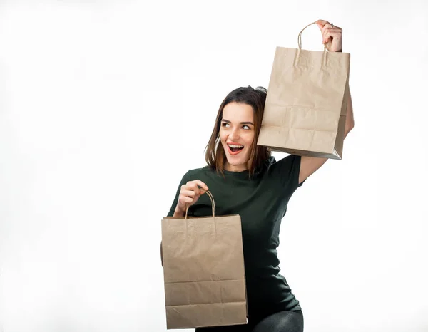よそ見しながらあらゆる手に買い物袋を上げる幸せな美しい女 ショッピング ファッションのコンセプトです 白い背景の独立したフロント ビュー — ストック写真