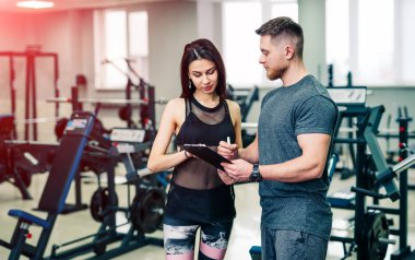 Personal fitness trainer assisting a young woman with workout. Fitness concept. clipart