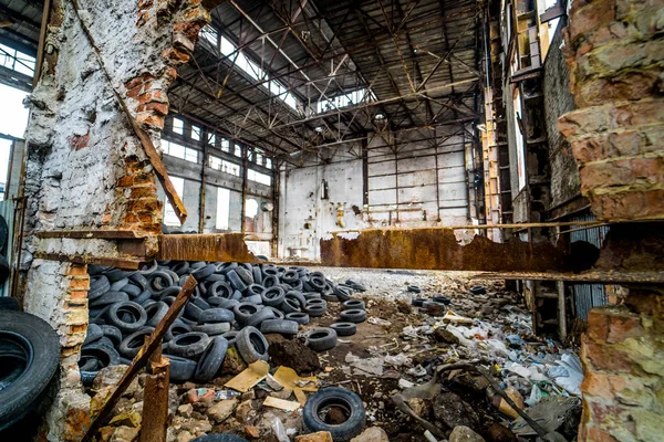 Destroyed old factory with garbage and a pile of used rubber tyres inside. Tires that are no longer suitable for use on vehicles in a damaged plant.