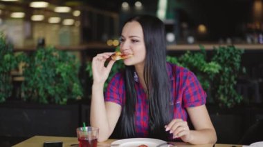 bir ekose gömlek güzel kız pizzacı bir masada pizza bir dilim yiyor