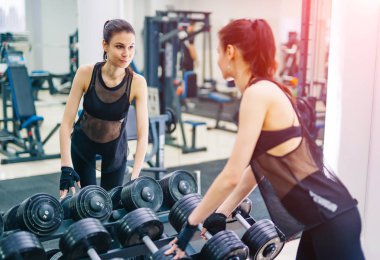 Atletik kadın kas dumbbells ile pompalama. Spor, fitness ve sağlıklı yaşam konsepti.