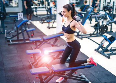 Spor salonunda egzersiz yapan güzel bir genç bayan. Kaslı vücutlu genç bir kadın. Fitness konsepti.