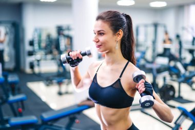 Kadın dumbbell kas vasıl jimnastik salonu ile egzersiz. Spor, fitness ve sağlıklı yaşam konsepti.