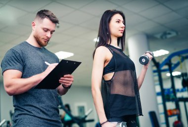 Ağırlık eğitim yardımı salonunda teknik direktörü ile sahip fitness kız. Kişisel fitness eğitmeni. Kişisel eğitim.