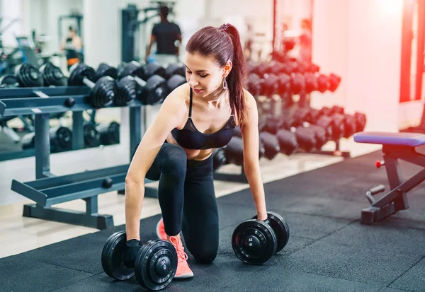Kadın dumbbell kas vasıl jimnastik salonu ile egzersiz. Spor, fitness ve sağlıklı yaşam konsepti.