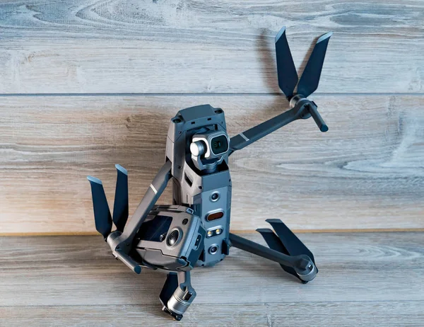 金属のドローンが手と足の木製の背景を持つ男の形で座っています。空中写真撮影のための現代 quadrocopter。クローズ アップ — ストック写真