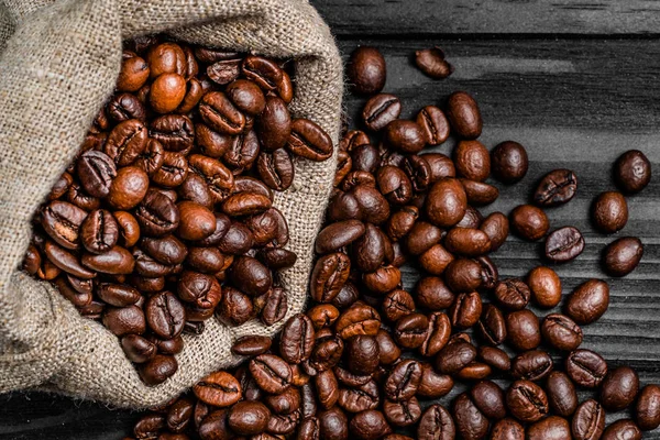 Közeli kép: barna Bio kávé babszemek hullanak a táskát. A rendetlenség az asztalon szétszórt zsák kávé magok és sült bab. Közeli kép:. — Stock Fotó