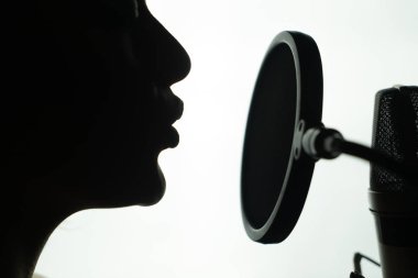 Siyah ve beyaz profil yuvarlak mikrofon şarkı genç bir kadın. Dişinin yüz mikrofon yakınındaki Close-Up.