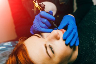 Dergi Close-Up dilinde özel araç ile dövme mavi eldiven eller. Genç kadın sürekli makyaj dudaklarından sahip. Yakın çekim