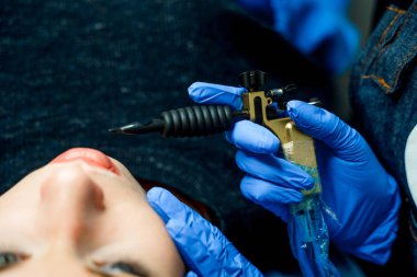 Kalıcı makyaj dudaklar Güzellik Salonu içinde güzel kadın için. Güzellik uzmanları Close-Up koruyucu eldiven dudaklarından dövme yapmak için özel araç tutan eller.