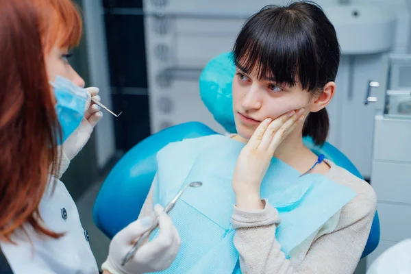 Eine junge Patientin zeigt dem Zahnarzt in der Zahnarztpraxis ihre Zahnschmerzen. Frauenbesuch beim Arzt in Zahnklinik. — Stockfoto