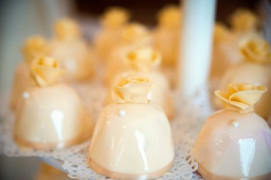 Üstüne güzel bir gül ile lezzetli krem kurabiye close-up. Konuklar için küçük beyaz peçete üzerinde lezzetli parlak tatlılar.