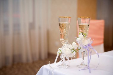 Restoranda beyaz masa örtüsü üzerinde romantik görünümü düğün gözlük şampanya ile. İki kristal bardak köpüklü şampanya ile beyaz çiçeklerle süslenmiş. Yakın çekim