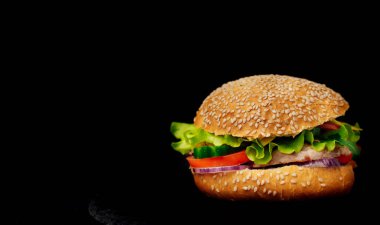 Lezzetli burger eti ve taze sebze siyah arka plan üzerine izole. Bir lezzetli biftek ağız sulandıran hamburger. Metin için yer