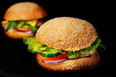 Sığır eti ve sebze koyu arka plan üzerinde ile iki büyük hamburger. Yeşil salata ile taze lezzetli sandviçler. Sağlıksız yiyecek. Yakın çekim