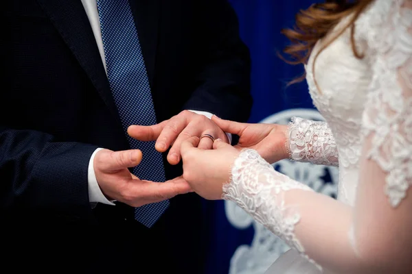 Sposa sta mettendo anello d'oro al dito dello sposo durante la cerimonia nuziale. Mani di una coppia amorevole con fedi nuziali — Foto Stock