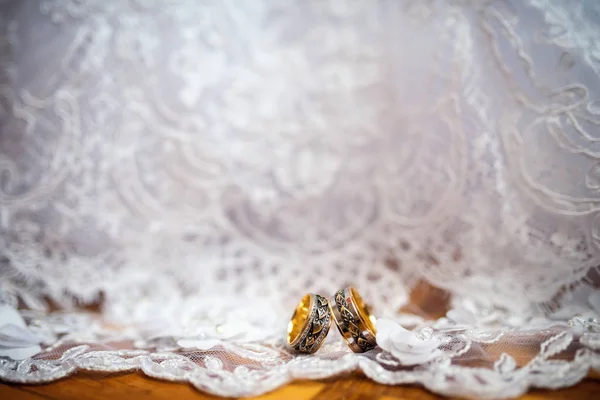 Dois anéis de casamento elegantes em um fundo vestido branco. Acessórios românticos para noiva e noivo. Jóias de casamento. Close-up — Fotografia de Stock