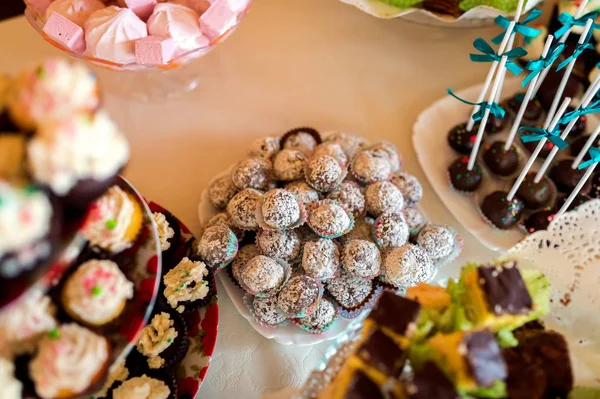 Pyszne ciasteczka na weselne dla Gości na biały obrus. Cake pops i lizaki, kolorowe babeczki, słodycze w formie bufetu. Szczelnie-do góry — Zdjęcie stockowe