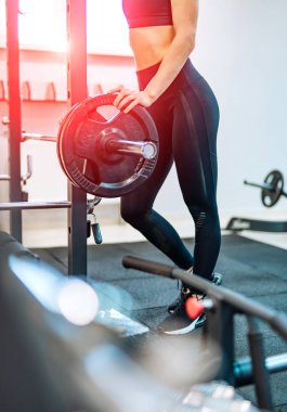 Spor kulübünde halter ile spor tozluklar yan görünüm sportif kadın bacaklar profili. Merkezinde kırmızı ışık sızıntıları ile büyük Halter Fitness modeli ayakta.