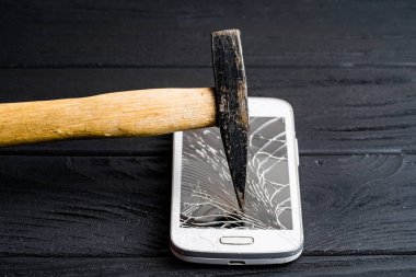 Hammer koyu arka planda izole modern duyusal Smartphone posalar. Pahalı cep telefonu büyük çekiç tarafından ahşap yüzeyde becerdin.