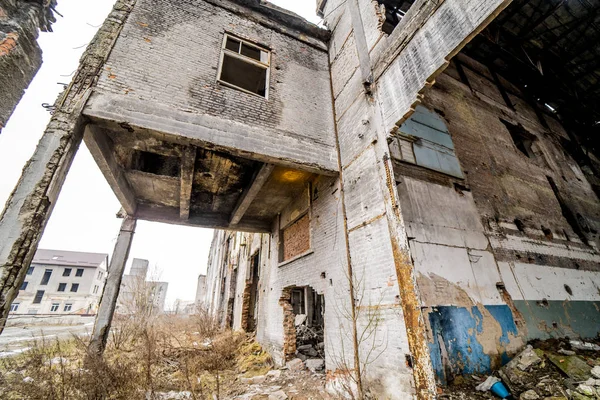 Broken-down destroyed industrial building outside. Old, ruined and collapsed abandoned building with columns by traditional cement bricks and stones.