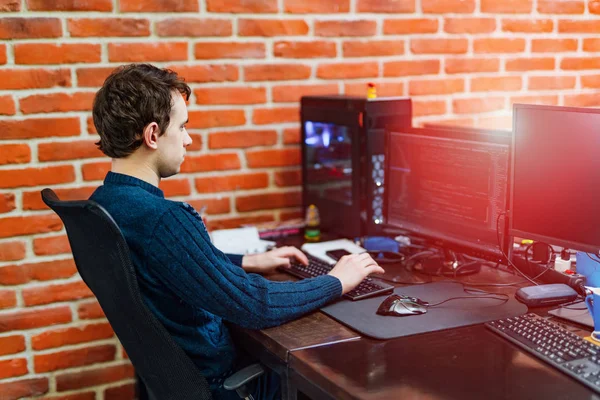 Programador está trabajando en una oficina de la compañía de desarrollo de software. Joven mirando el monitor de computadora mientras trabaja en la programación de computadoras. Diseño del sitio web . — Foto de Stock